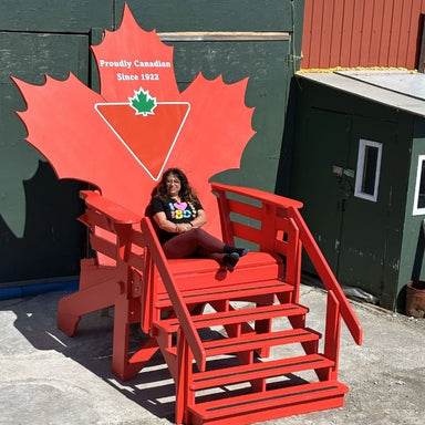 Person sitting on 10' Maple Leaf Giant Chair with a Canadian flag design.