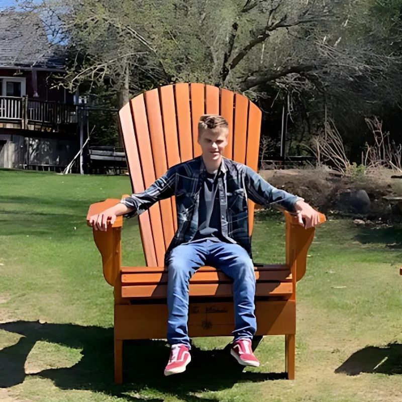 Man sitting on Customized Giant orange  chair outdoors.
