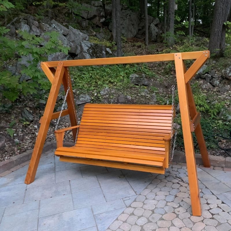 Wooden swing set in a garden setting with greenery and rocks.