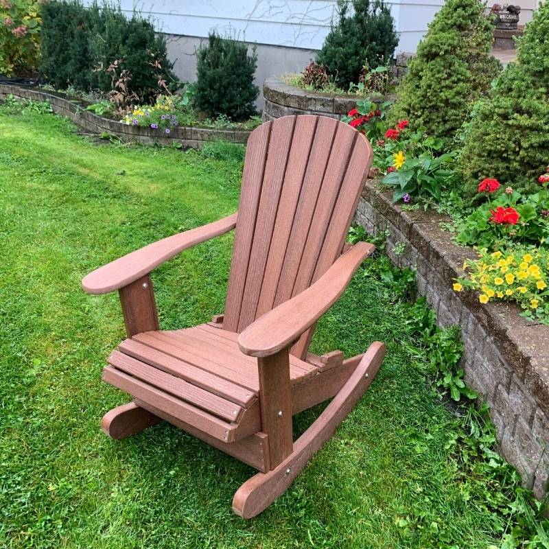 Royal Rocking Adirondack Chair (Large) in a garden setting with flowers and greenery.