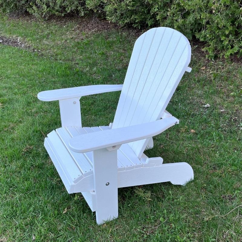 White Royal Upright Adirondack Chair, on a grassy area with greenery in the background