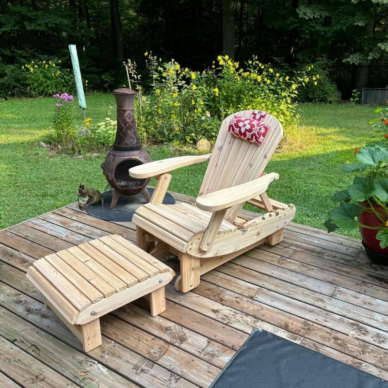 Royal Reclining Glider with ottoman on a wooden deck with a garden background