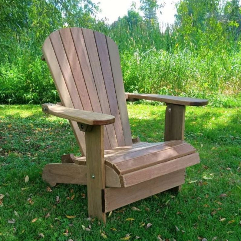 Royal Upright Adirondack Chair, on a grassy area with greenery in the background