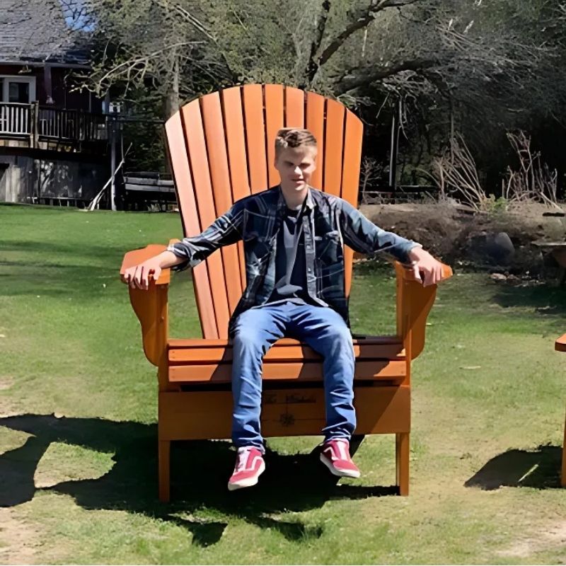 Person sitting on Traditional Giant chair outdoors on a grassy area.