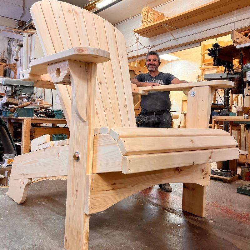 Man in a workshop with Traditional Giant chair he has been working on.