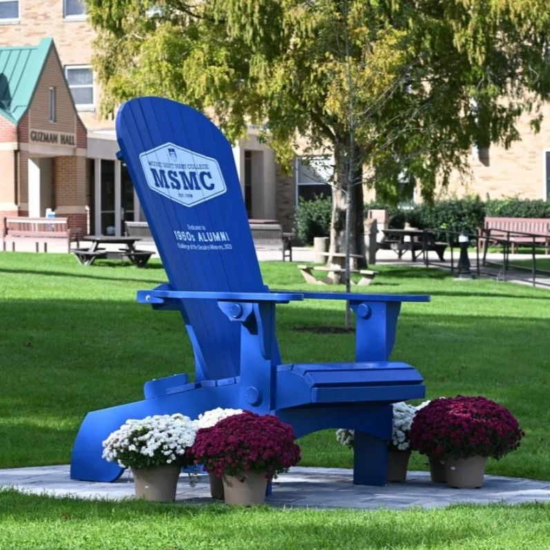 Blue Traditional Giant with MSMC logo on a grassy area with flowers and a building in the background