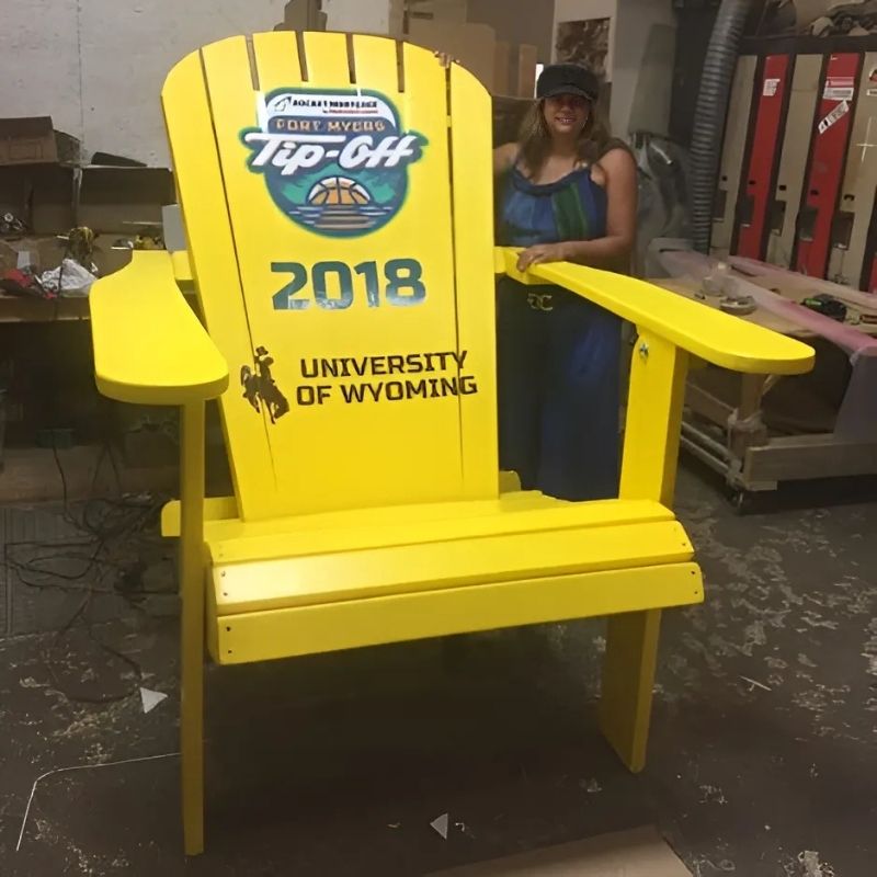 Traditional Giant yellow chair with 'University of Wyoming' and '2018' text, held by a person in a workshop.