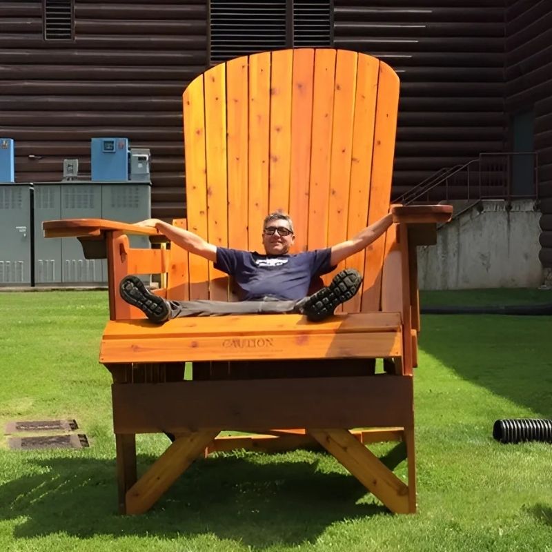 Person sitting on Traditional Giant orange chair outdoors