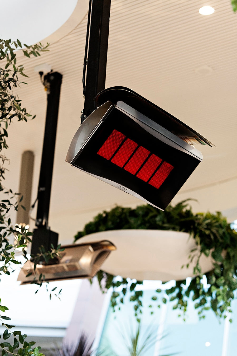 Bromic Platinum gas heaters glowing over an outdoor patio, ceiling pole mounted