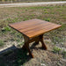 24" Square Side Table in a natural outdoor setting with greenery - clear cedar - caramel glossy