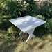 24" Square Side Table in a natural outdoor setting with greenery - clear cedar - golden glossy in a natural setting with greenery - poly luxe - white