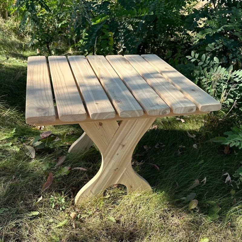 Wooden table in a natural outdoor setting with grass and plants - Knotted Cedar variant