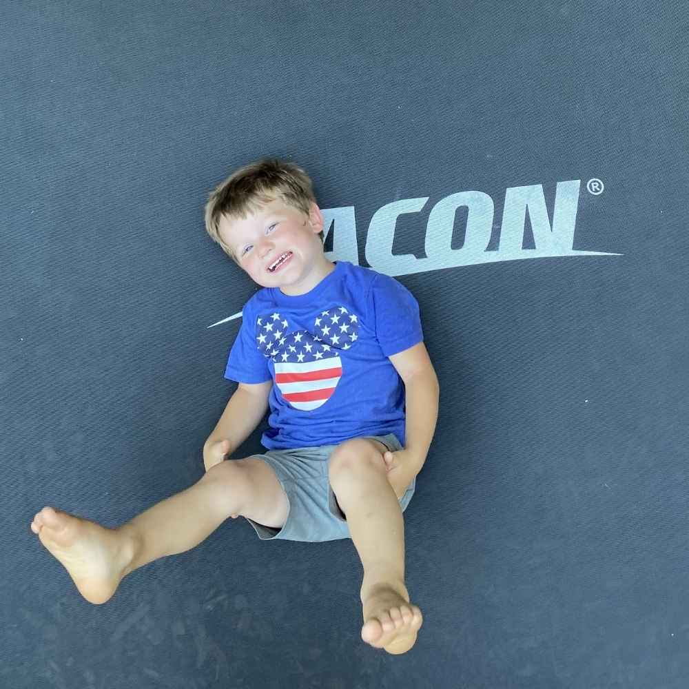A happy boy lying on an Acon trampoline.