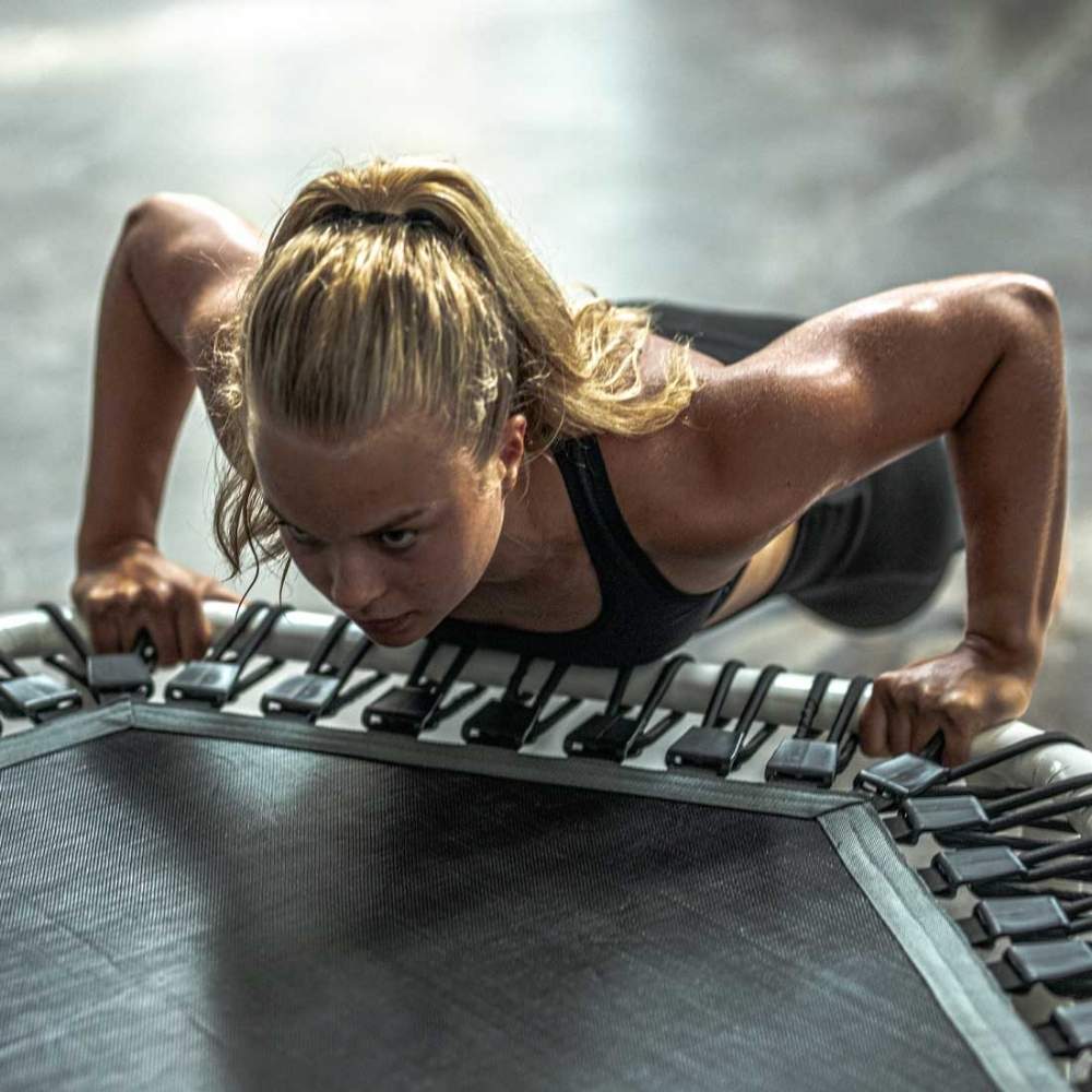 Woman exercising on the Acon FIT 1,41m white Hexagon trampoline