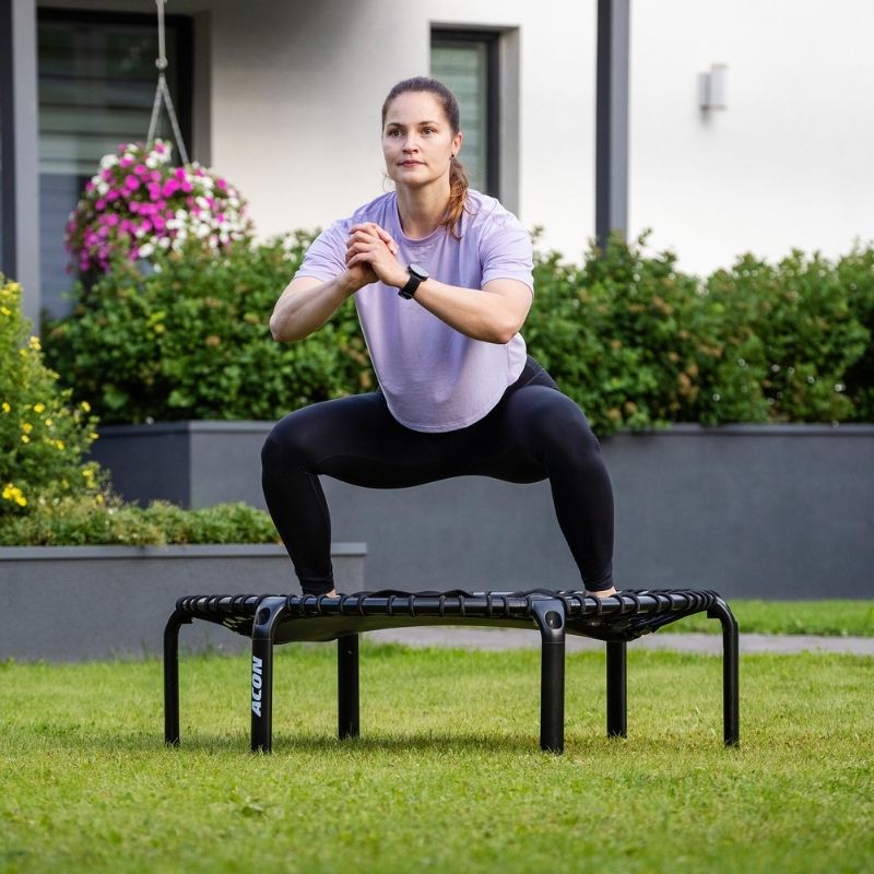 ACON Fit 1.41m Hexagon Rebounder Black Fitness Trampoline with Handlebar - Woman exercising on a rebounder in a garden