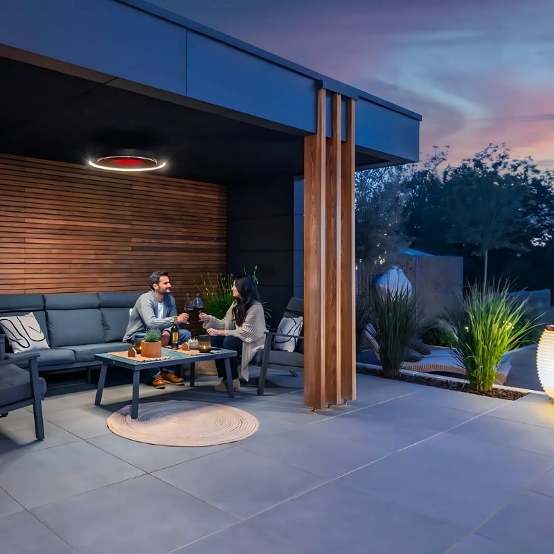 Modern outdoor patio with people sitting on a couch and table, evening setting.