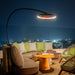 Outdoor evening setting with a sofa, chairs, and a table on a balcony with city lights in the background.