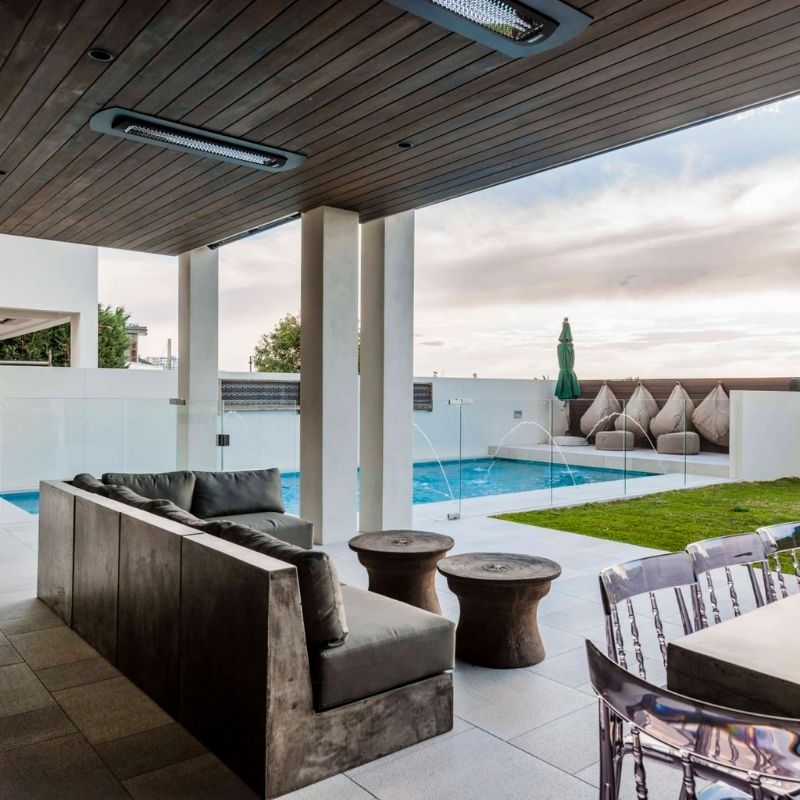 Ceiling installed in modern outdoor patio with pool area, seating, and glass walls.