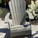 Classic Adirondack Chair (Standard) on a patio with flowers in the background - poly luxe - woodgrain driftwood grey
