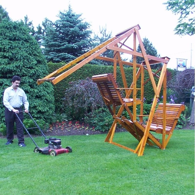 Man mowing grass next to a classic graden swing set in a garden.