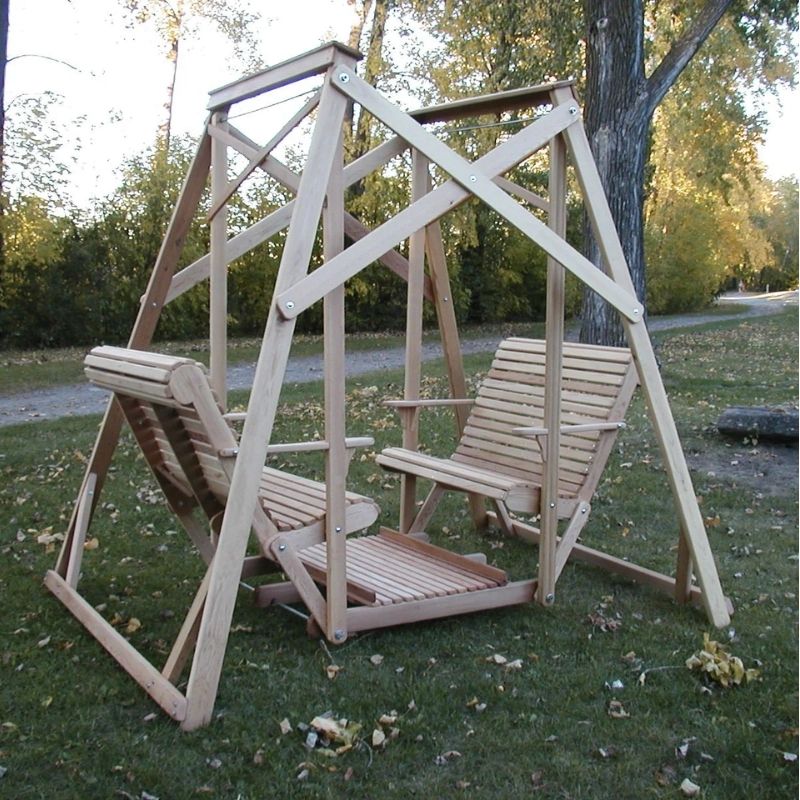 Classic graden swing set with two chairs on a grassy area with trees in the background
