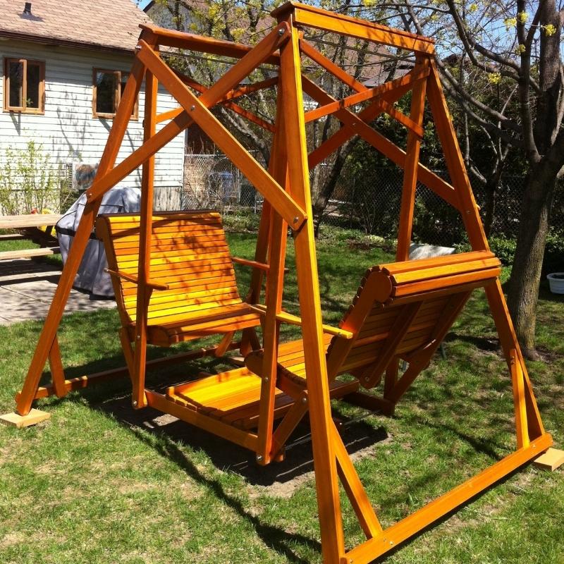 Classic graden swing set in a backyard with grass and trees
