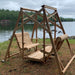 Classic graden swing set by a lake with trees in the background