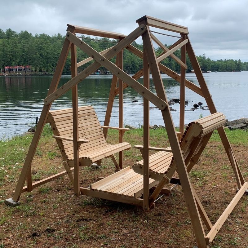 Classic graden swing set by a lake with trees in the background