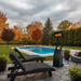 Outdoor patio with pool, black lounge chairs, and a standing outdoor heater in a garden setting.