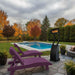 Purple lounge chairs by a pool with a patio heater on a cloudy day.