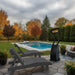 Outdoor patio with dark grey lounge chairs, pool heater, and fire pit in a backyard setting.
