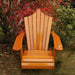 Wooden Adirondack chair on a patio with greenery in the background - peak back  golden glossy - clear cedar