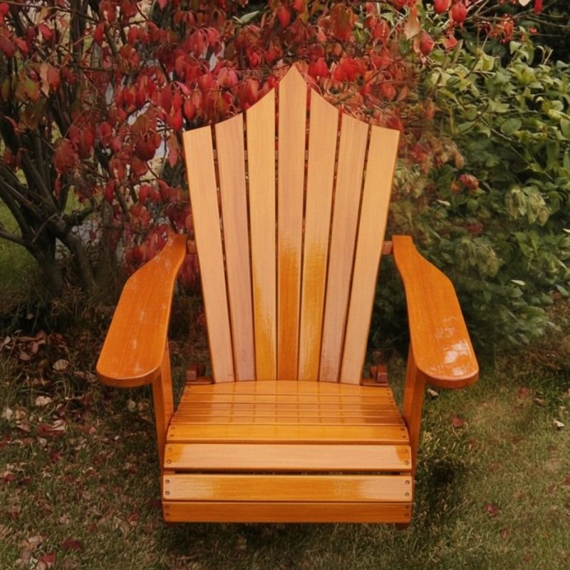 Wooden Adirondack chair on a patio with greenery in the background - peak back  golden glossy - clear cedar