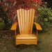Wooden Adirondack chair on a patio with greenery in the background - wave back  golden glossy - knotted cedar