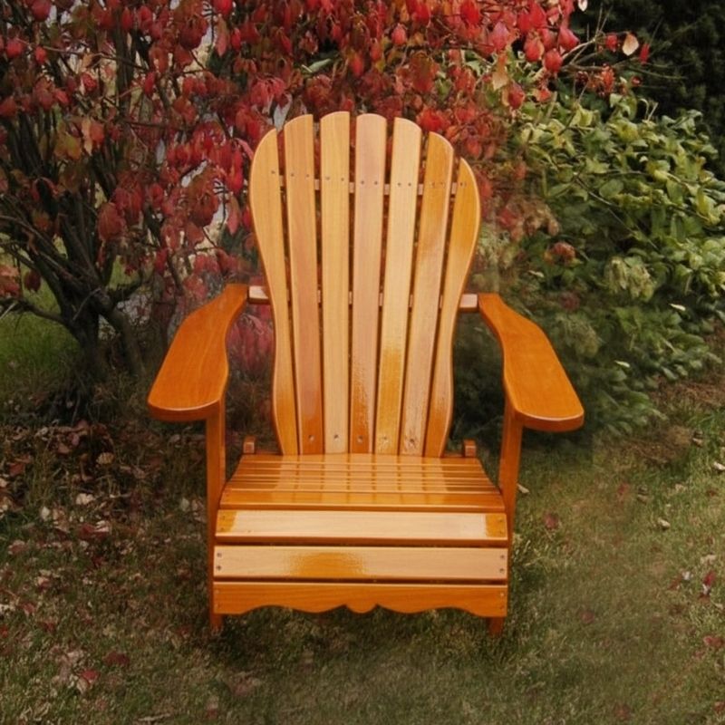 Wooden Adirondack chair on a patio with greenery in the background - sandal back  golden glossy - clear cedar