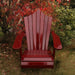 Wooden Adirondack chair on a patio with greenery in the background - peak back  mahogamy glossy - clear cedar