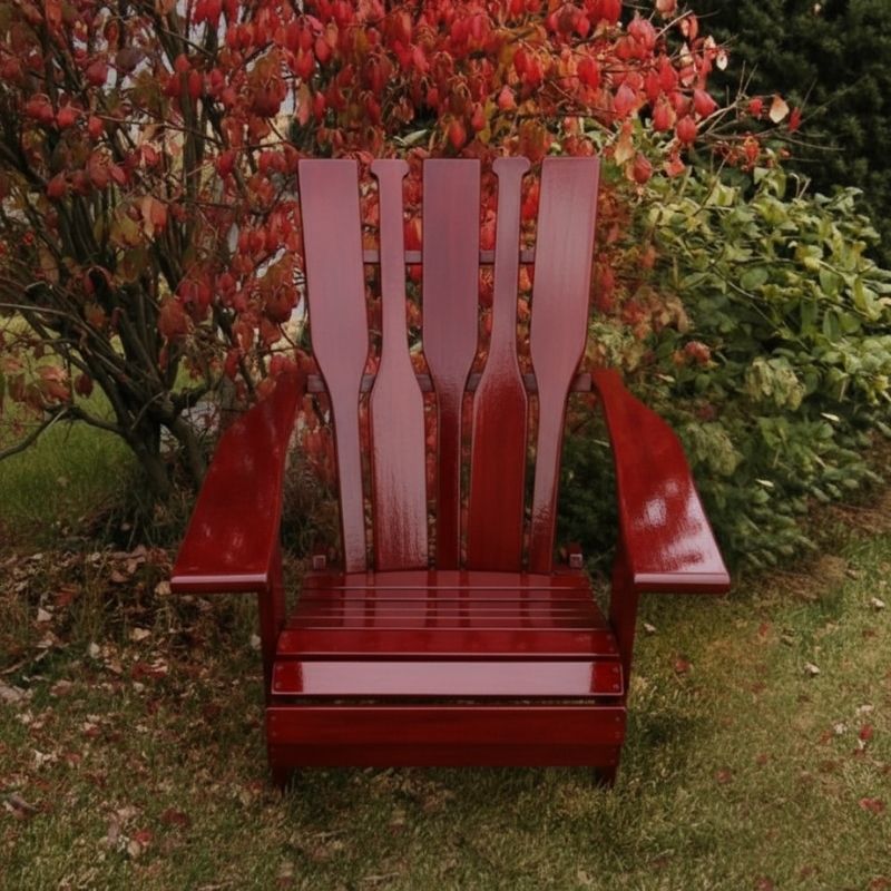 Wooden Adirondack chair on a patio with greenery in the background - puddle back  mahogamy glossy - clear cedar