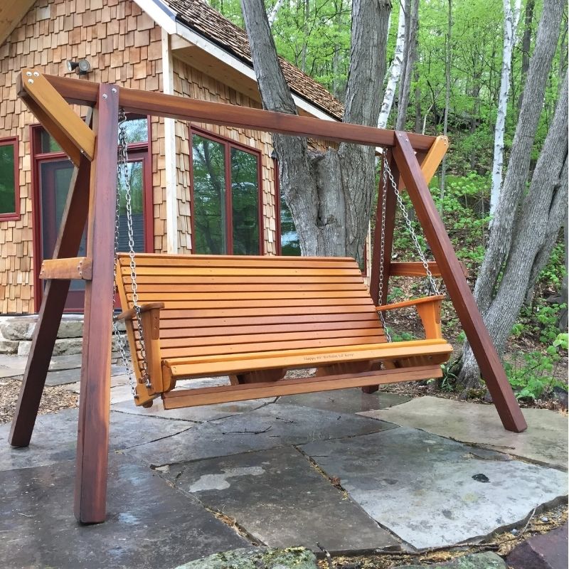 Family Porch Swing with Frame in front of a cabin with trees in the background