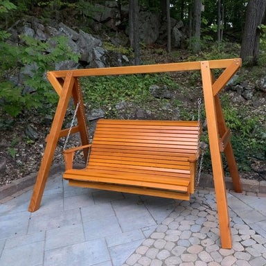 Wooden swing set in a garden setting with greenery and rocks.