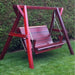 Family Porch Swing with red frame on a grassy area with green bushes in the background