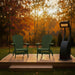 Two turf green Adirondack chairs on a wooden platform with a heater in an autumn setting.