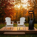 White Folding Muskoka Portable Comfort Bundle in a patio  and autumn trees in the background.