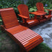 Set of mahogany red wooden chairs and a table on a stone patio with greenery in the background