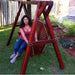 Woman sitting on a red swing set in a backyard