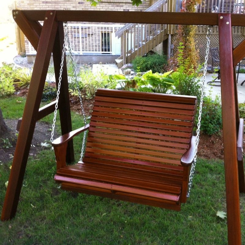 Wooden swing hanging from a stand in a garden setting