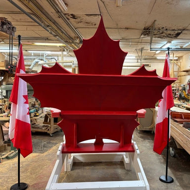 Maple Leaf Giant Chair in a workshop with Canadian flags on either side