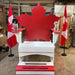 Two dogs on red and whiteMaple Leaf Giant Chair a Canadian flag in an indoor setting.