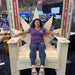 Woman sitting on Marijuandack Giant with promotional signs at a convention center.