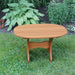 Oval Side Table in a grassy area with plants in the background - poly luxe - cedar