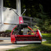 Red Rolux X25 - 25" Reel Style Lawn Mower on a grassy area with a house in the background